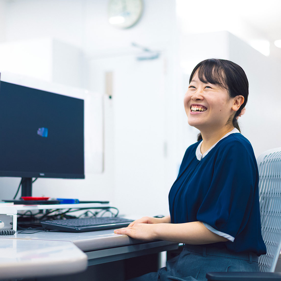 笑顔でデスクに座る国内営業の女性社員
