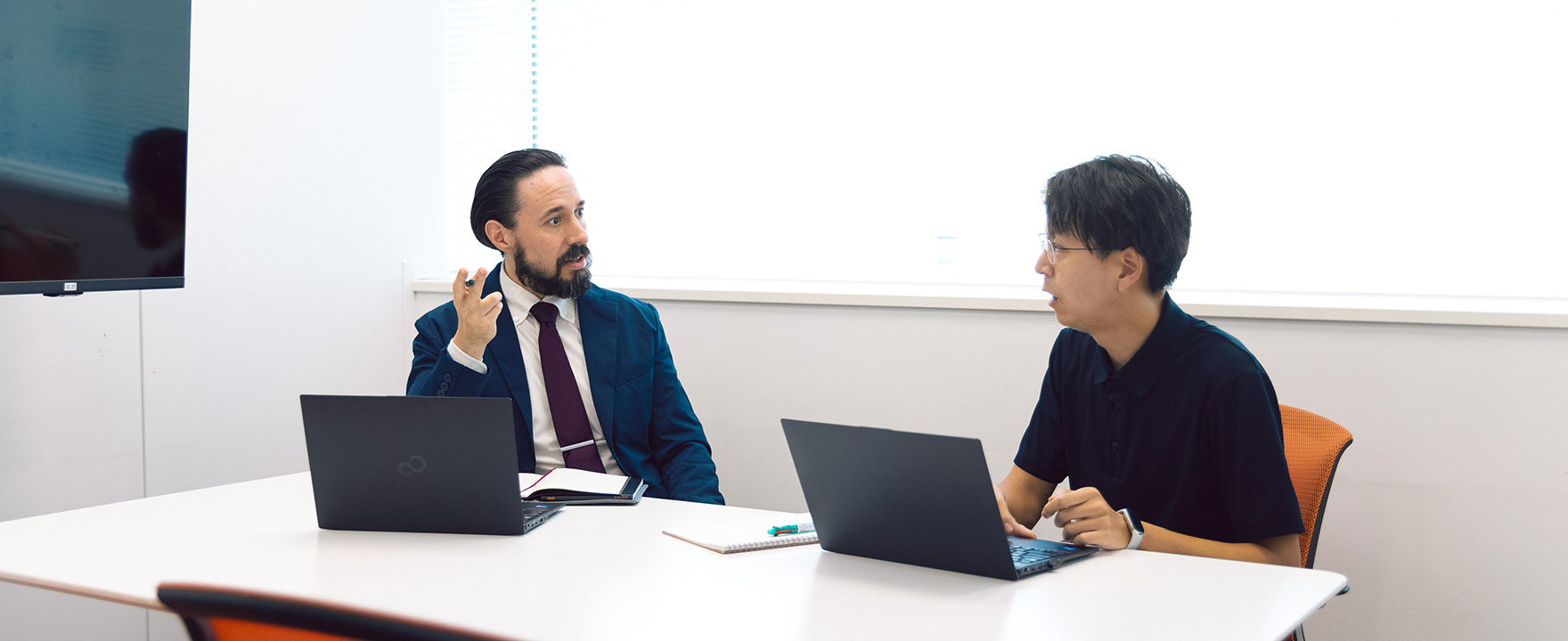 同僚に仕事内容を相談する国際営業の男性社員